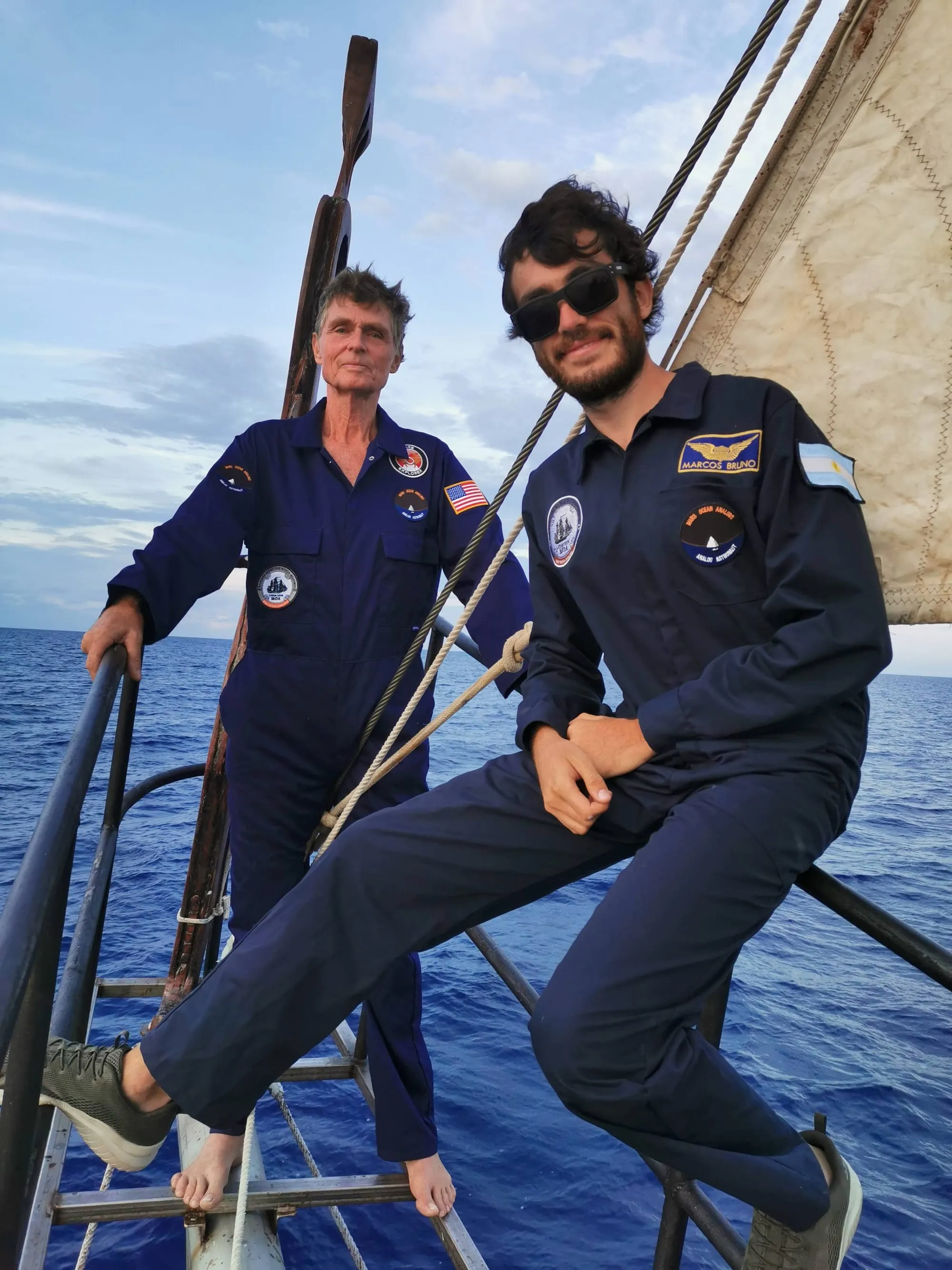 Marcos Bruno and Reid Stowe in expedition uniforms aboard the schooner, mid-crossing