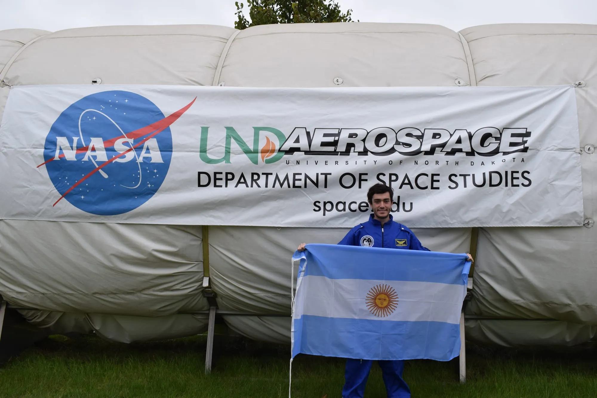 Marcos Bruno holds the Argentine flag in front of NASA’s ILMAH habitat