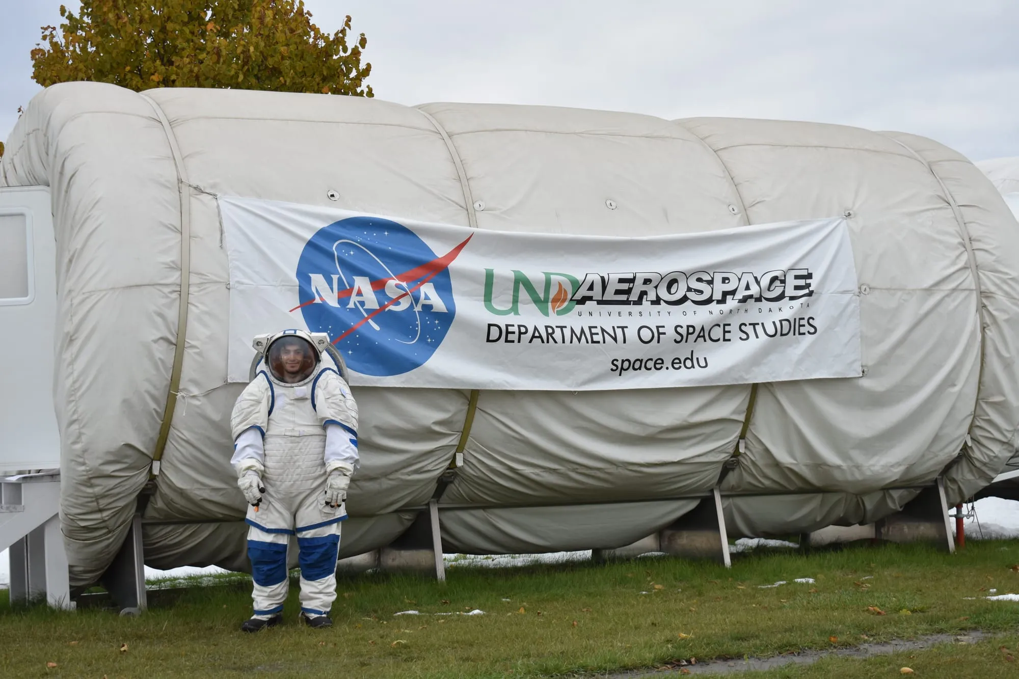 Marcos Bruno in a spacesuit in front of the ILMAH inflatable habitat at the University of North Dakota