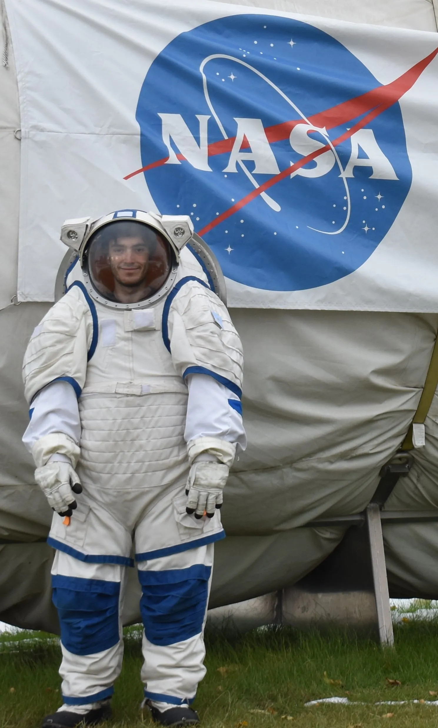 Marcos Bruno in an experimental spacesuit in front of the NASA logo at the ILMAH habitat